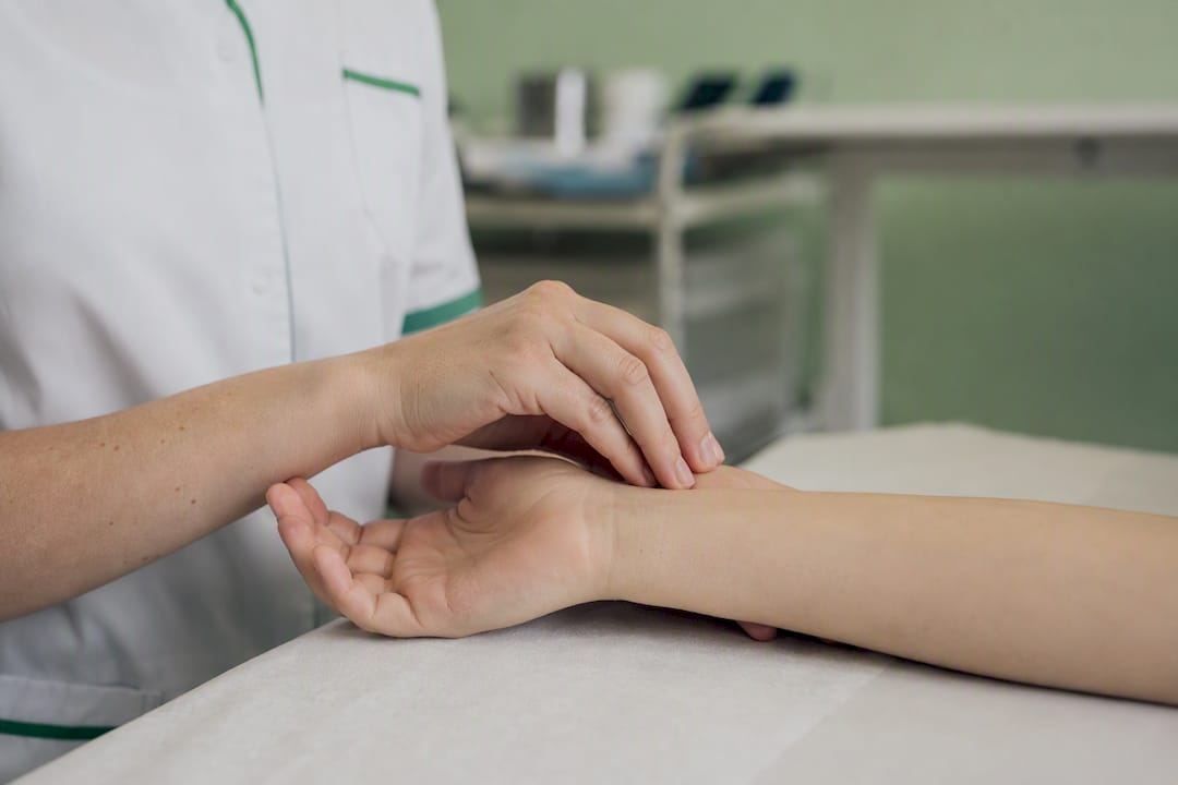 Un soignant tapote délicatement le poignet de son patient.